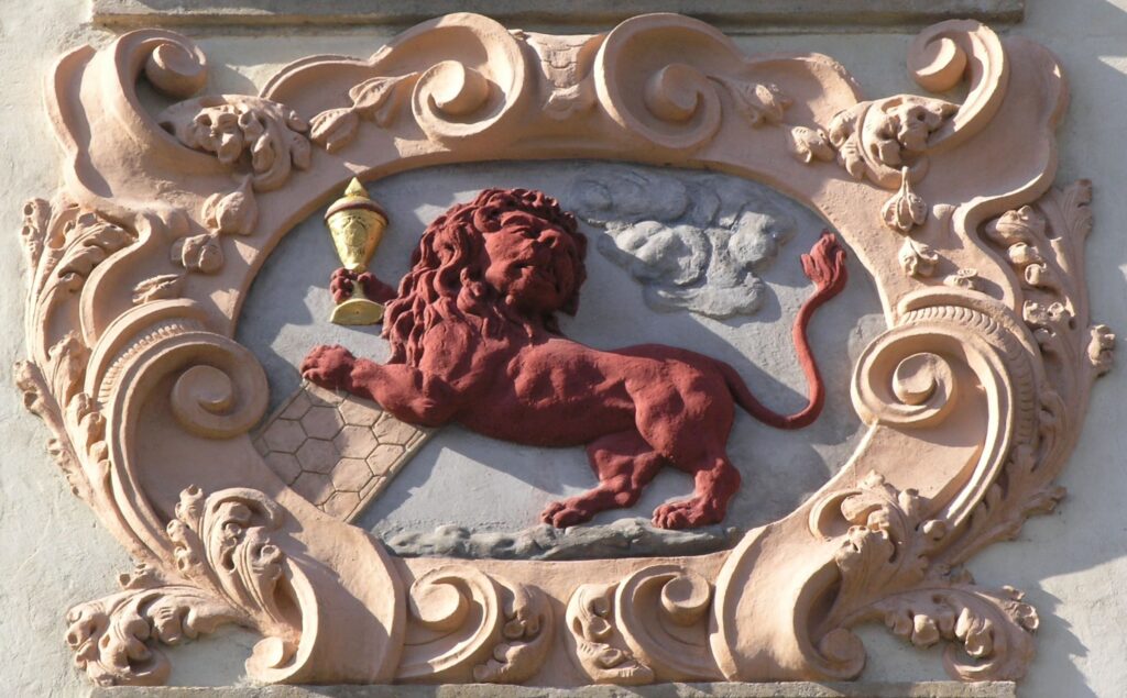 Domovní znamená na domě U Červeného lva v Nerudově ulici na Malé Straně (Foto: Matěj Baťha, Wikimedia Commons, licence Creative Commons Attribution-Share Alike 2.0 Generic)